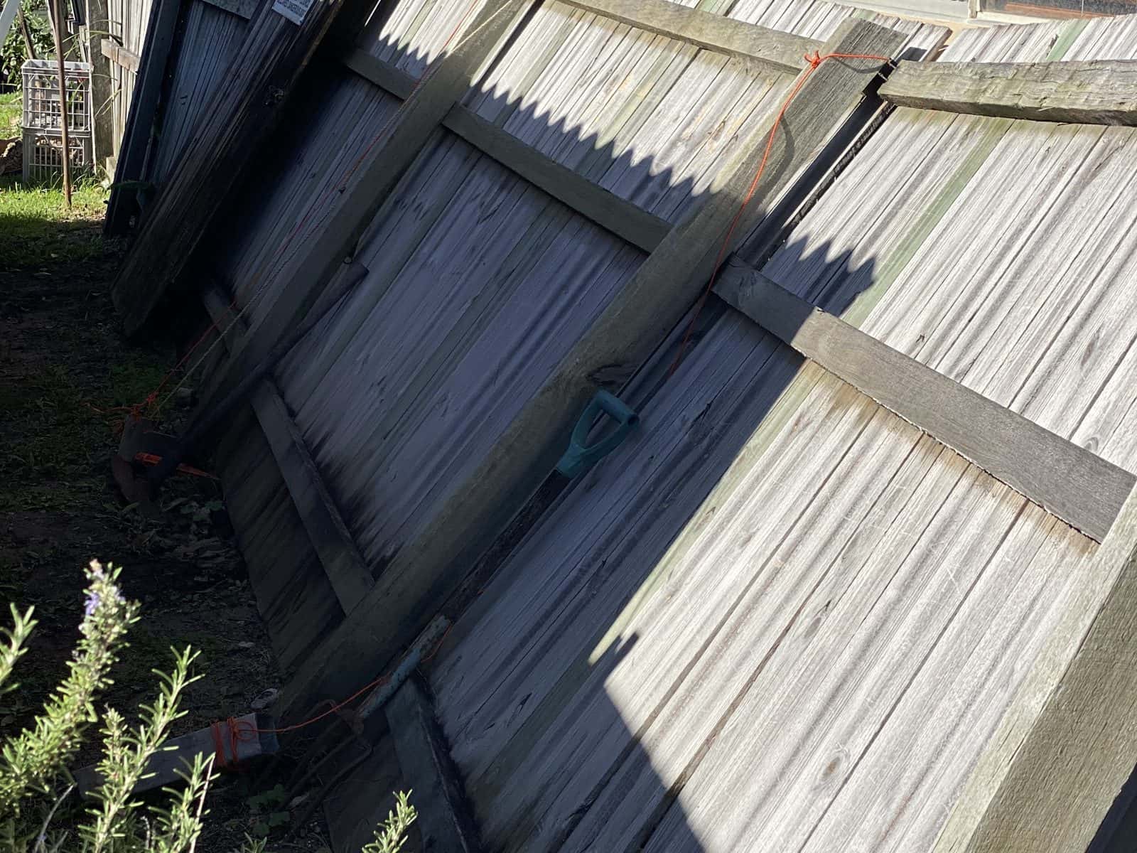 Leaning timber paling fence before repair