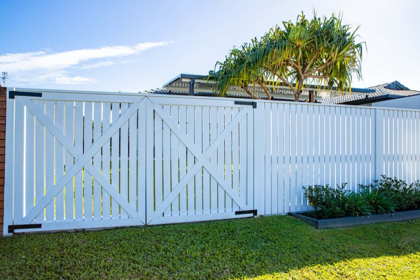 White double gates with cross bracing in a slat fence