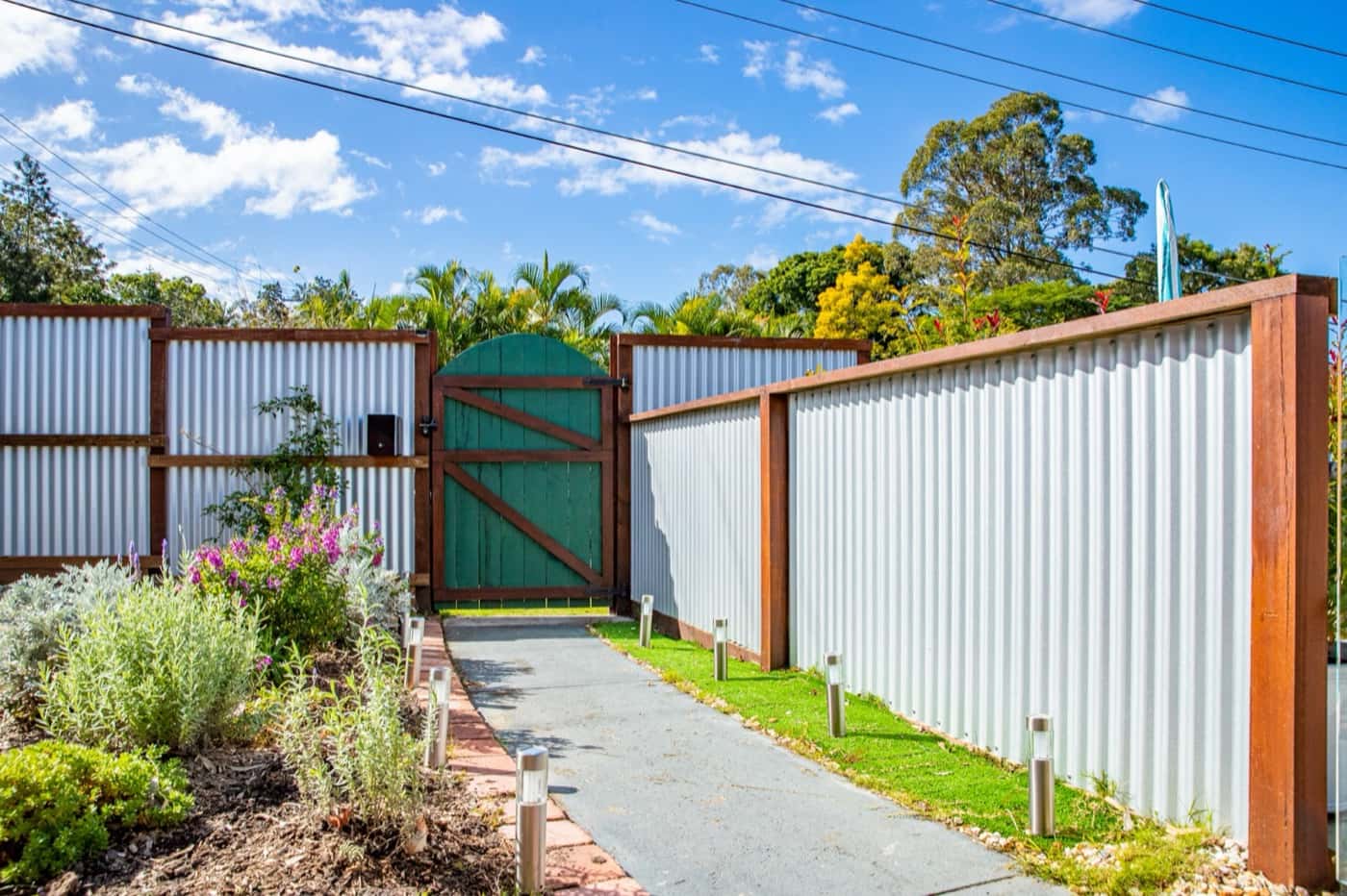 Green Colorbond gate framed in timber at the end of a garden path