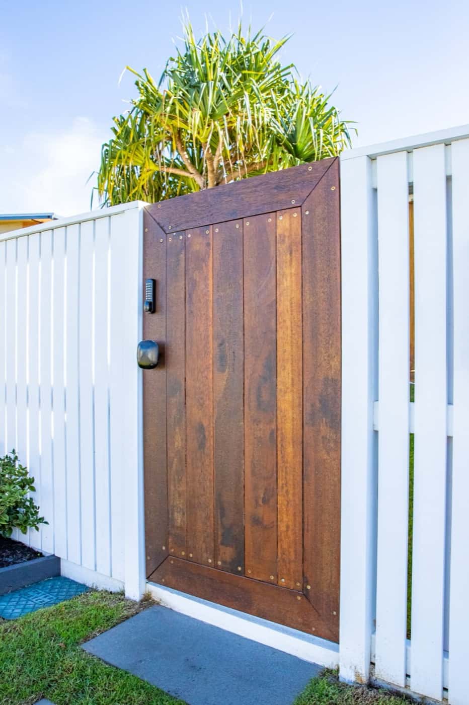 Close up of a stained timber pedestrian gate in a white fence