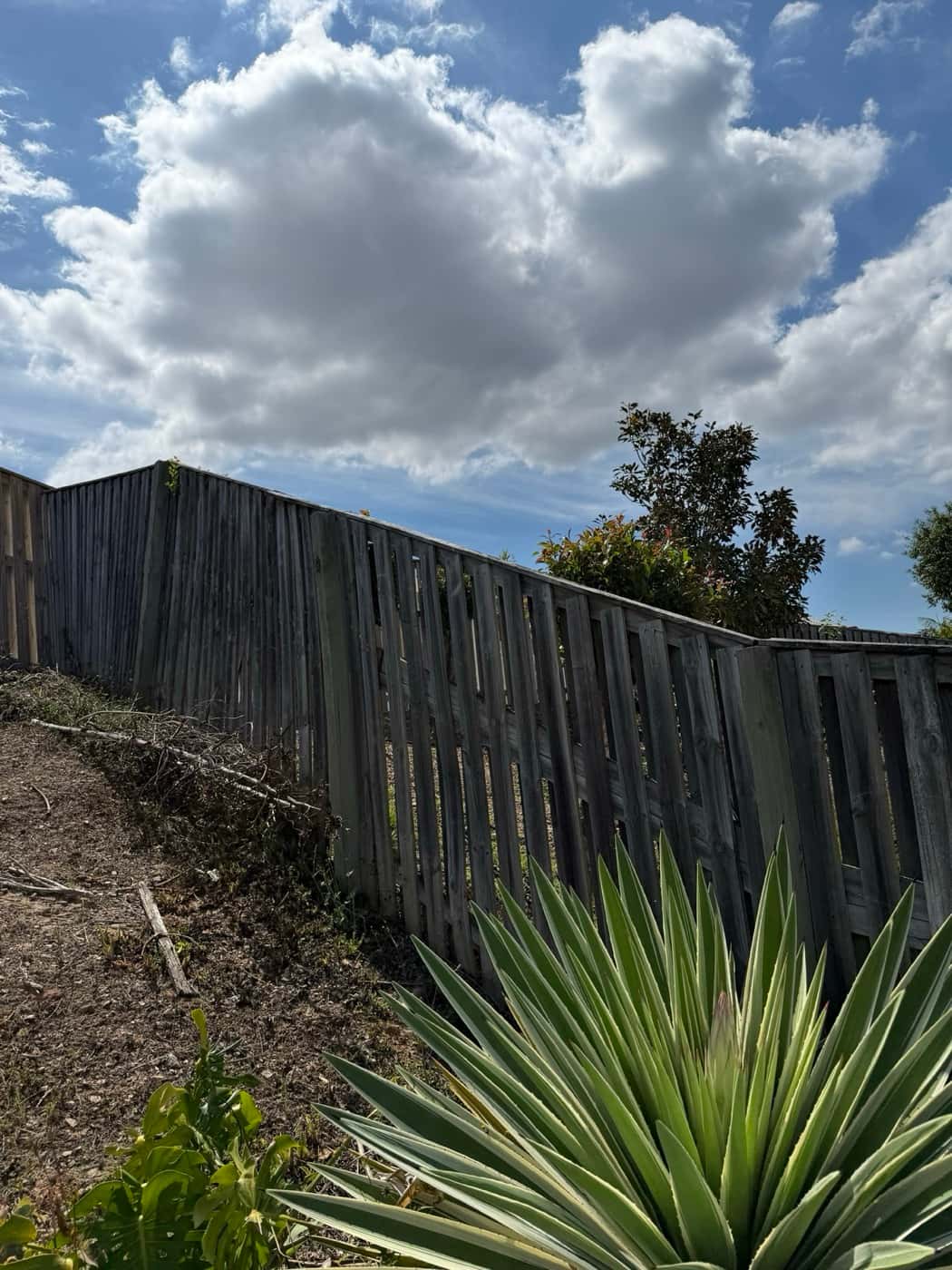 Timber fence on a slope leaning over before repair