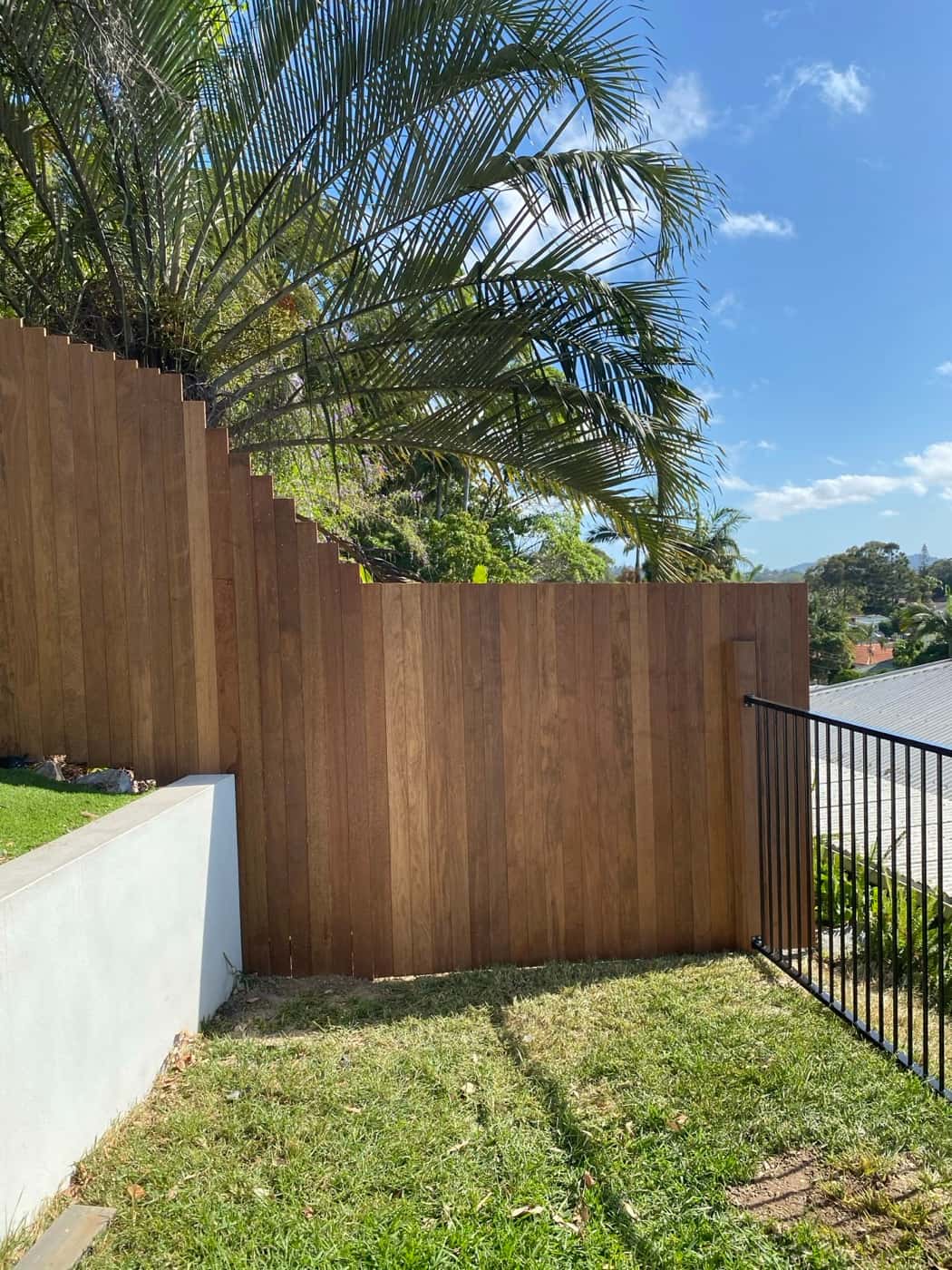 Stained timber fence stepping down above a rendered wall