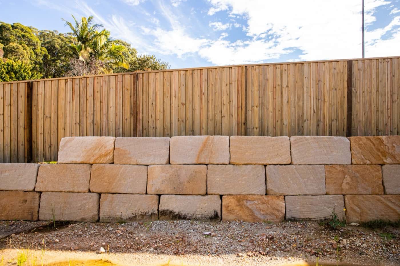 Timber paling fence on top of sandstone block retaining wall