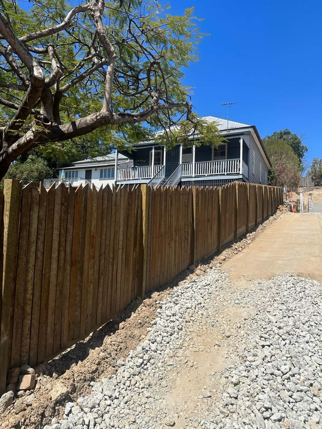 Stained paling fence running down a gravel side path